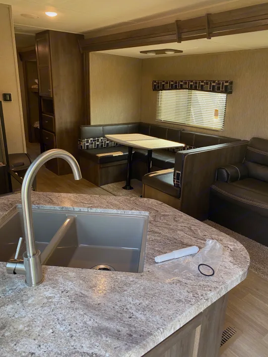 Modern RV rental interior showcasing a well-equipped kitchen, dinette, and living area. Ready for adventures.. Dutchmen Coleman 2019