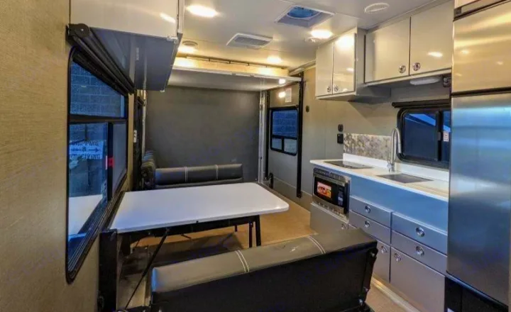 Explore this modern RV rental interior featuring a versatile living area, full kitchen, and rear multi-purpose space with elevated bunk.. Aluminum Trailer Company 2816 2021