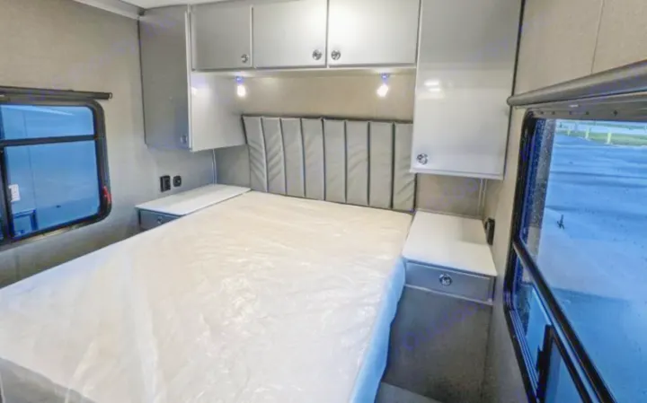 RV rental interior: cozy bedroom featuring a bed, upholstered headboard, overhead cabinets, and practical side tables.. Aluminum Trailer Company 2816 2021
