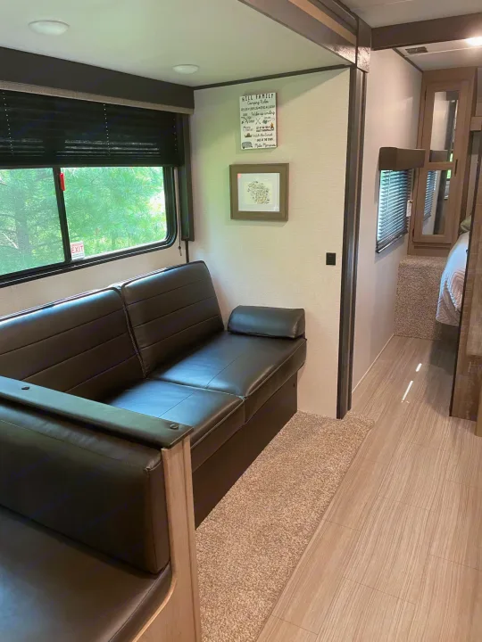 RV rental living space with comfy seating, a window view, and a hallway leading to the bedroom area.. Keystone Hideout 2021