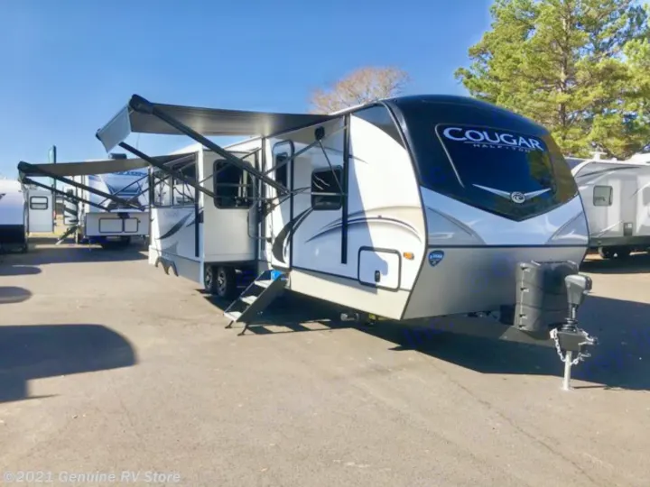 A sleek white and black Cougar travel trailer RV, featuring extended awnings, is ready for your next rv rental adventure.. Keystone Cougar Half-Ton 2021