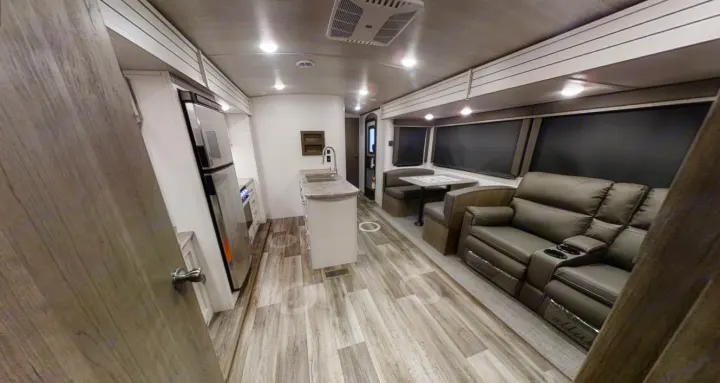 This RV rental offers a well-appointed recreational vehicle interior featuring a kitchen, dining area, and reclining sofa.. Keystone Cougar Half-Ton 2021