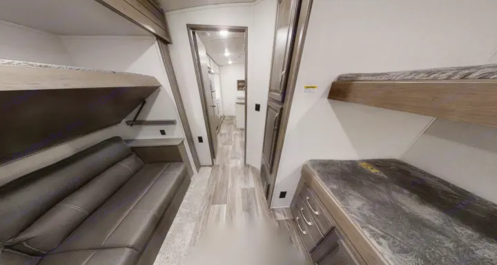 Inside an RV rental: bunk beds on both sides, a sofa, and a hallway leading to a kitchen area.. Keystone Cougar Half-Ton 2021