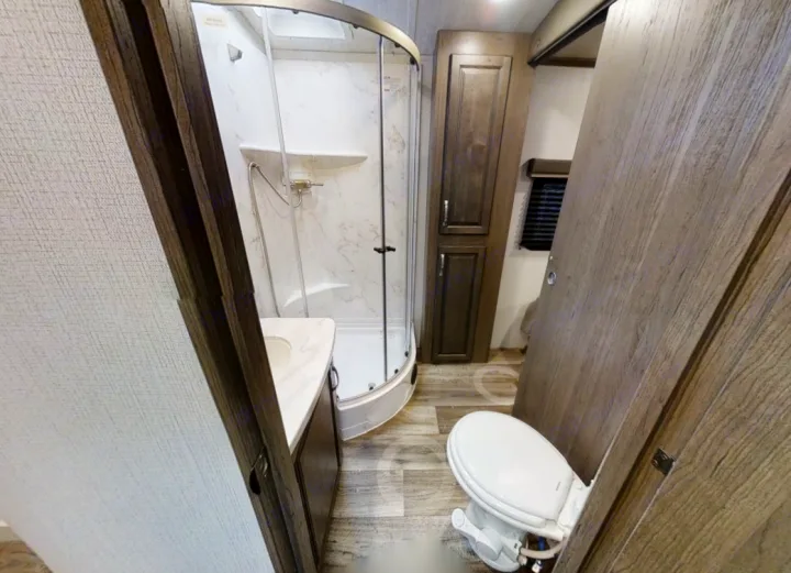Modern RV rental bathroom with compact design, glass shower, bidet-equipped toilet, and vanity sink.. Keystone Cougar Half-Ton 2021