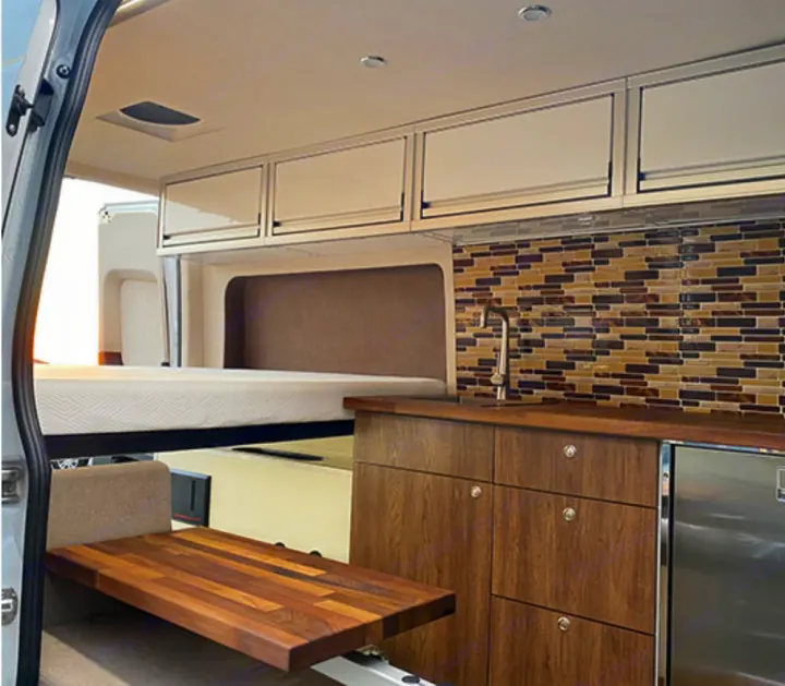 RV rental interior featuring a cozy bed, sleek kitchenette with mosaic backsplash, and smart storage solutions.. Mercedes-Benz Sprinter 2020