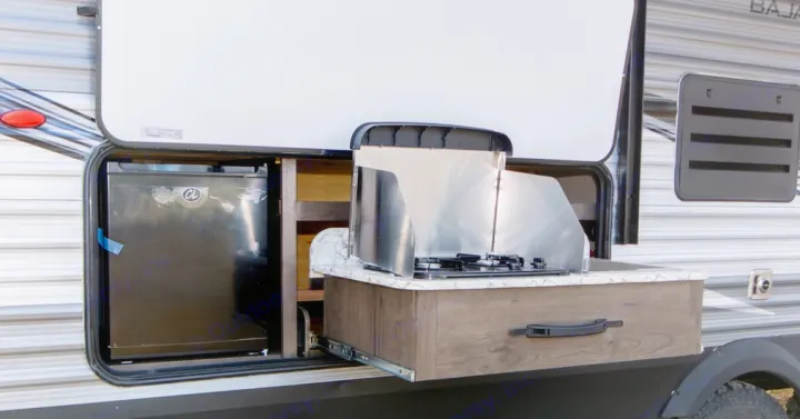 Side of an RV with an open compartment revealing a mini-fridge & pull-out counter with stove. Great for an rv rental.. Jayco Jay Flight 2021