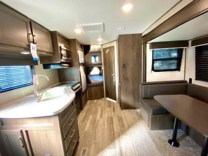 Spacious rv rental interior featuring a modern kitchen, dining area with booth seating, and bunk beds.. Jayco Jay Flight 2021