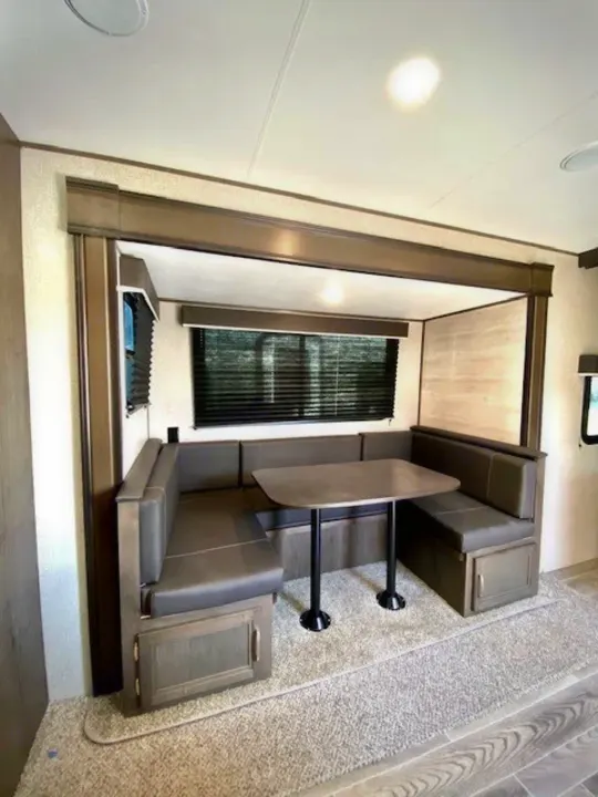 Interior of an RV rental showing a grey U-shaped dinette with a table, ideal for dining or relaxing in comfort.. Jayco Jay Flight 2021