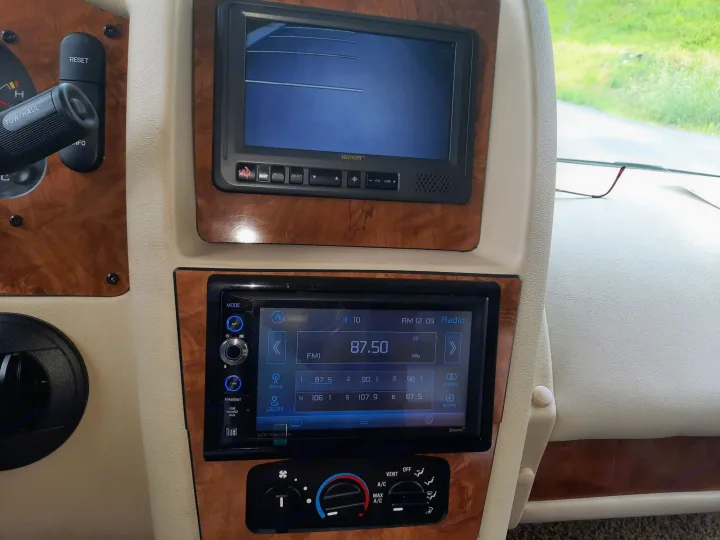Interior RV rental view: dashboard with a rearview monitor, multimedia stereo, and climate controls.. Ford Coachman 2009