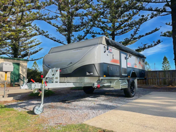 A sleek, grey and black Jayco Swan Outback caravan, perfect for your next RV rental or adventure, parked at a sunny campsite.. Jayco Swan Outback 2021