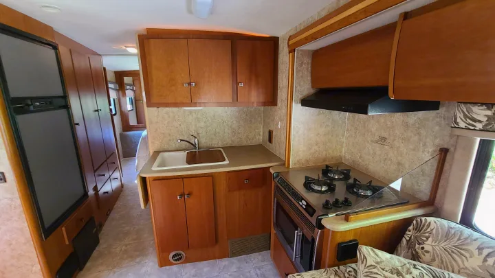 Spacious RV rental interior showcasing a full kitchen with a fridge, sink, oven, stovetop, and ample cabinets.. Itasca Spirit 2007