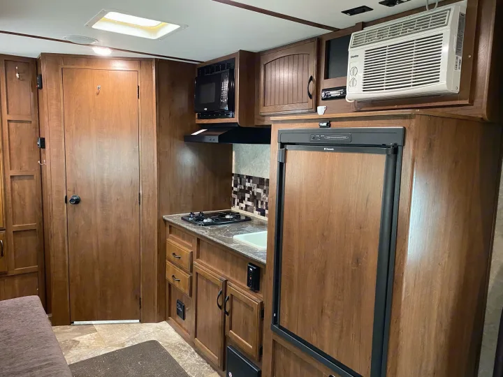Clean and functional RV rental interior: features a kitchen with microwave, fridge, stove, and a visible AC unit.. Jayco Jay Feather 2017