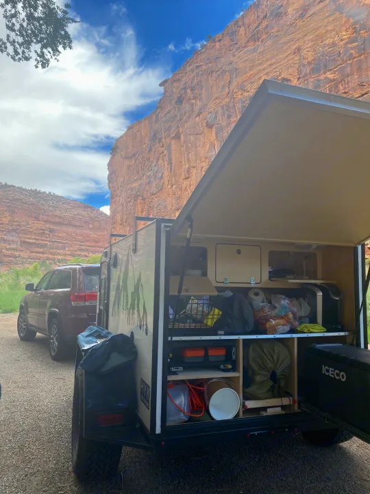 Adventure-ready RV rental trailer with an organized outdoor kitchen, parked in a rugged canyon landscape for camping.. Other Other 2021