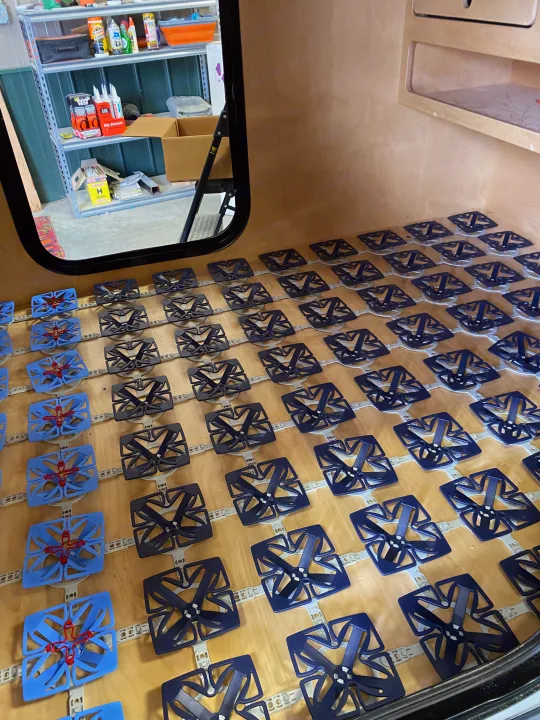 Inside an RV, a modular bed base with flexible blue and dark grey elements creates comfortable sleeping for an RV rental.. Other Other 2021