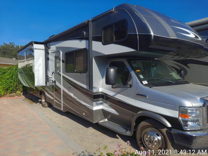 Spacious silver/black Class C rv rental, parked outdoors with slide-out extended for camping adventures.. Forest River Sunseeker 2018