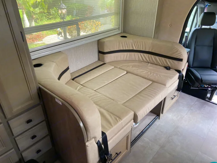 This RV rental's interior features a light-colored dinette that converts into a bed, with drawers & window views.. Mercedes-Benz Sprinter Coachmen Prism 2021