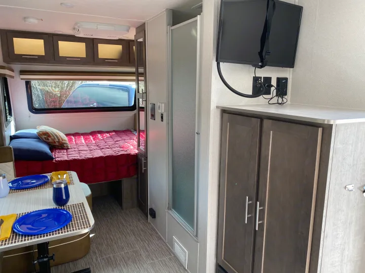 Step inside this cozy RV rental interior, featuring a comfortable bed, dining area, and mounted TV.. Forest River Other 2019
