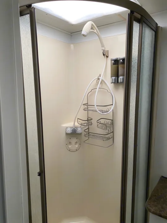 Compact RV rental shower interior with handheld sprayer, soap dispensers, and storage caddy.. Forest River Georgetown 2011