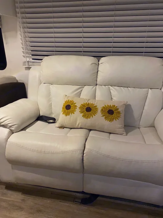 Spacious RV rental interior: white multi-section sofa with a sunflower pillow and privacy blinds.. Forest River Georgetown 2011