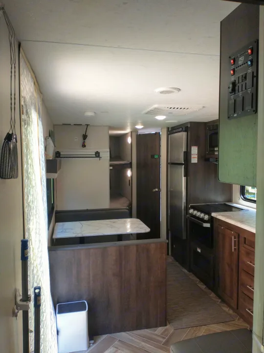 RV rental interior: A practical and comfortable space featuring a kitchen, dinette, and bunk beds for travelers.. KZ Sportsmen 2021