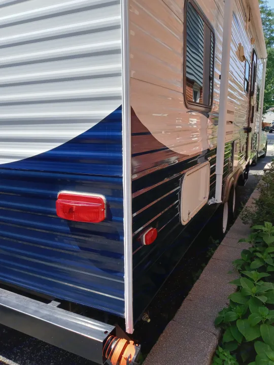 Modern blue & beige travel trailer, ideal for an rv rental adventure. Features striped siding, windows, and white wheels.. Holiday rambler Traveler 2013