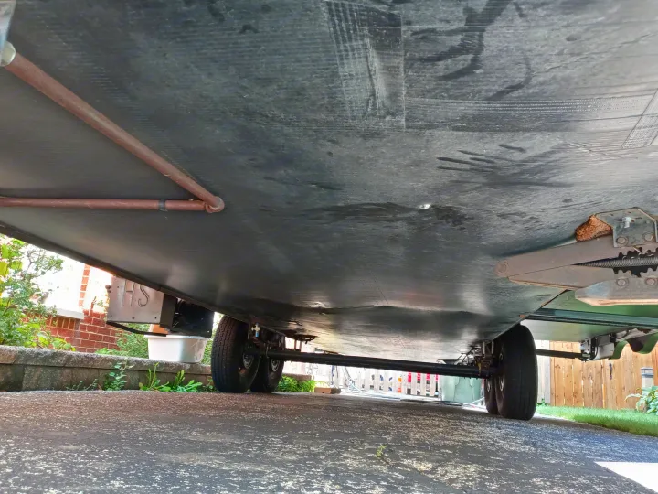 Low-angle view of an RV rental's underside: black underbelly, tires, and utility lines visible, ideal for pre-trip inspection.. Holiday rambler Traveler 2013