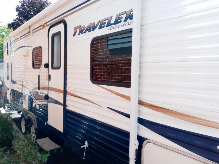 Side view of a white and blue Traveler by Holiday Rambler RV rental, featuring an awning and accessible door.. Holiday rambler Traveler 2013