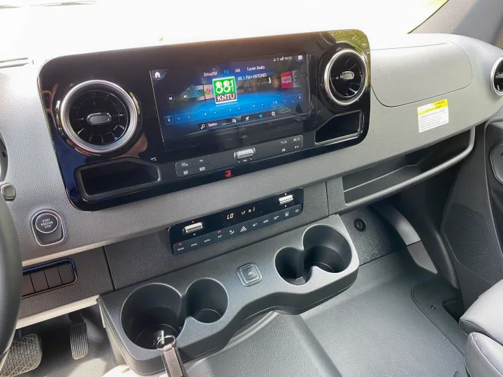 RV rental interior: Dashboard with infotainment screen, climate controls, cup holders, and push-button start.. Mercedes-Benz Sprinter 2021