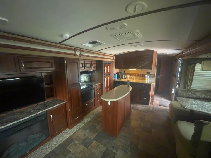 Inside an RV rental: a modern kitchen with an island, living area with TV & fireplace, and comfortable seating.. Keystone 316-UL 2014