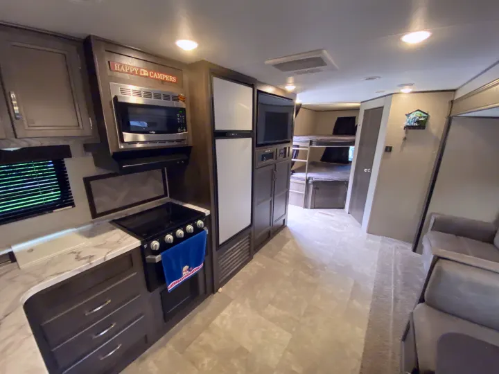 Modern RV rental interior showing a full kitchen (microwave, stove, counters), bunk beds, and living space.. Jayco Jay Flight 2020