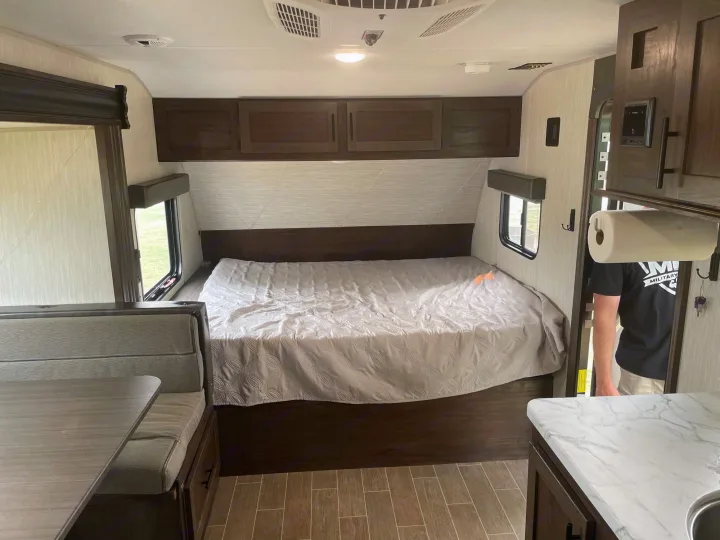 This RV rental interior offers a comfortable bed, dinette, and compact kitchen area.. Forest River Cherokee Wolf Pup 2020