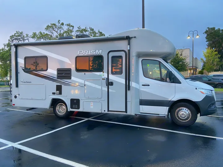This Coachmen Prism RV rental, a sleek Class C motorhome, is parked in a wet lot, ready for your next adventure.. Mercedes-Benz Sprinter Coachmen Prism 2021