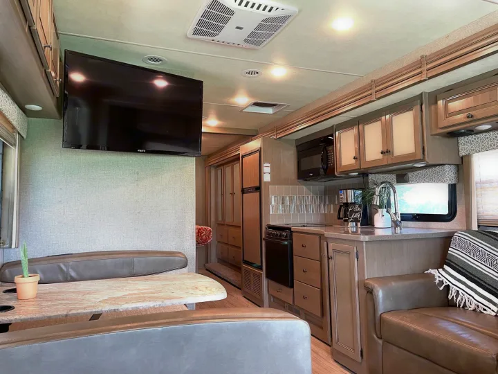 This RV rental interior shows a full kitchen, dining area, TV, and lounge for comfortable travel.. Thor Windsport 2020