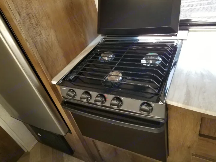 Clean RV rental kitchen featuring a black Dometic stove/oven with three burners and a silver refrigerator.. Forest River Salem Cruise Lite 2021