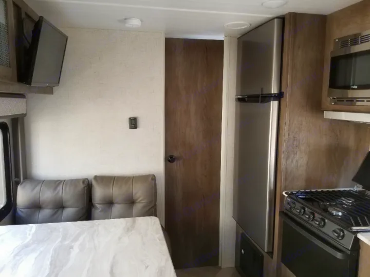 Modern RV rental interior with dinette, mounted TV, and a complete kitchen featuring a fridge, microwave, and stove.. Forest River Salem Cruise Lite 2021