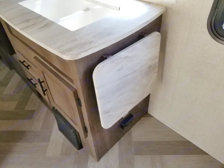 A compact RV kitchen area with a sink, wood cabinets, and an extendable counter, ideal for any RV rental trip.. Forest River Salem Cruise Lite 2021