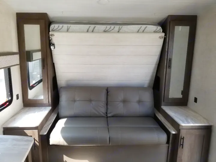 RV rental interior: a versatile space with a gray sofa, folded murphy bed, and mirrored storage cabinets.. Forest River Salem Cruise Lite 2021