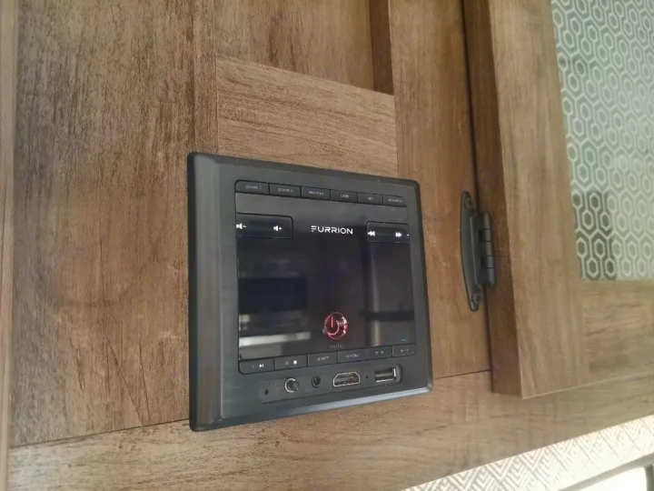 A Furrion media system is mounted on wood in an RV rental, featuring audio controls, USB, and HDMI ports.. Forest River Salem Cruise Lite 2021