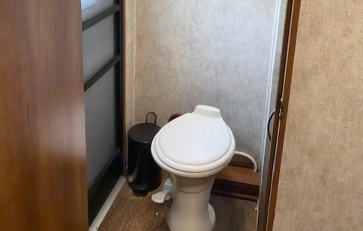 RV rental bathroom: a white toilet, black bin, and practical amenities in a compact space. Ready for travel.. Forest River Crusader BH 2015