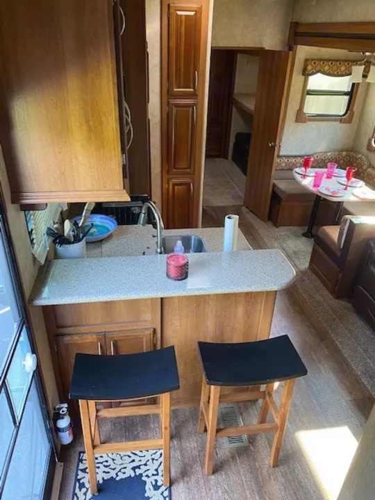 RV rental interior: cozy kitchen, dining booth, and bunk access. Perfect for family adventures!. Forest River Crusader BH 2015