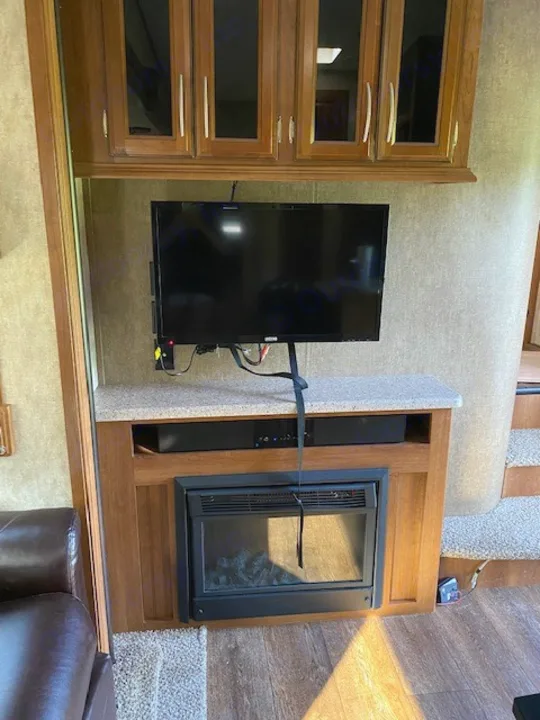 Enjoy this RV rental's cozy living area with TV, entertainment console, & electric fireplace, plus storage cabinets.. Forest River Crusader BH 2015
