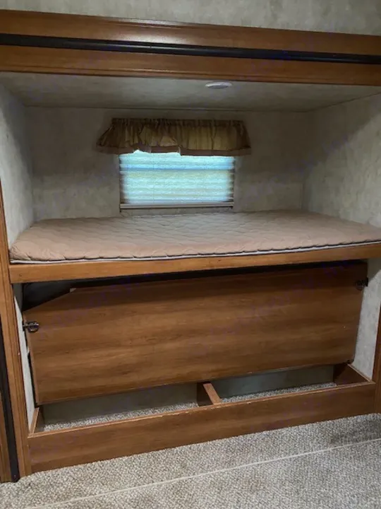 Cozy RV rental bunk bed setup with window and lower storage, ideal for compact travel.. Forest River Crusader BH 2015