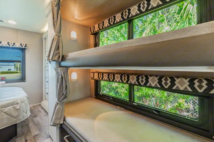 Inside this cozy RV rental, find comfortable bunk beds with reading lights and scenic window views, ideal for family adventures.. Jayco Redhawk 2022