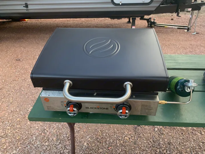 Portable Blackstone griddle with propane tank on a table at an RV rental site, ready for camping outdoor cooking.. Jayco Flight 2021