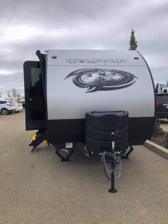 Front view of a "Wolf Pup Limited" travel trailer, perfect for an RV rental. Door open, stabilizers extended.. Forest River Wolf Pup 2021