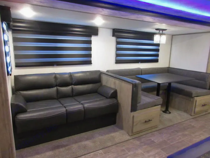RV rental interior featuring a comfy black sofa and U-shaped dinette with storage. Perfect for family adventures.. Forest River 30DBH-L 2021
