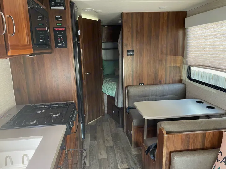 Explore this RV rental's spacious interior, featuring a well-equipped kitchen, comfortable dinette, and private bedroom area.. Winnebago Outlook 2020