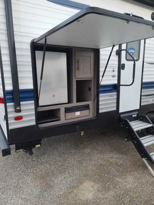 RV rental outdoor kitchen revealed on RV side, showcasing refrigerator, cooktop, and storage for convenient outdoor dining.. Keystone Springdale 2021