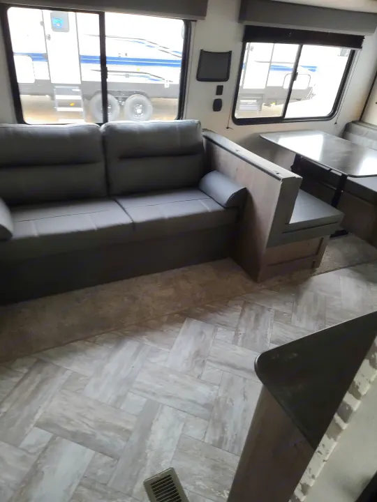 RV rental interior with a grey sofa, U-shaped dinette, and light wood-look floor.. Keystone Springdale 2021