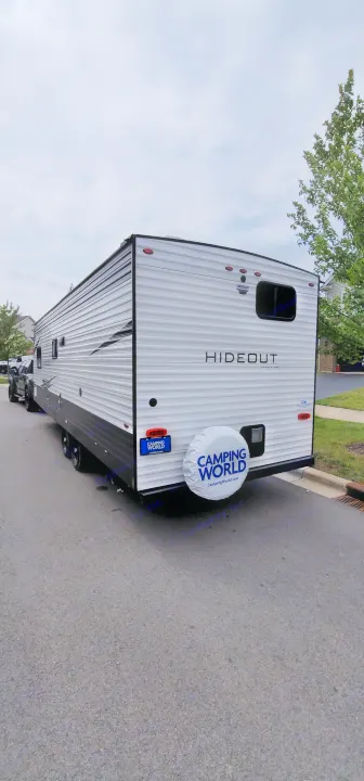 Rear view of a white Hideout travel trailer, ideal for an rv rental, featuring Camping World branding on its spare tire.. Keystone Hideout 2021